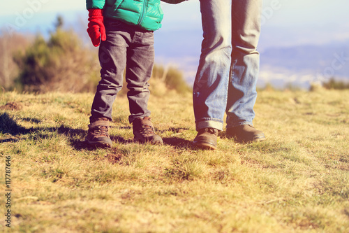father and little son hiking boots in mountains