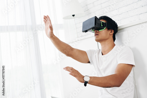 Young man in VR headset touching invisible objects