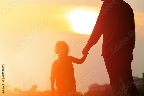 silhouette of father and daughter holding hands at sunset