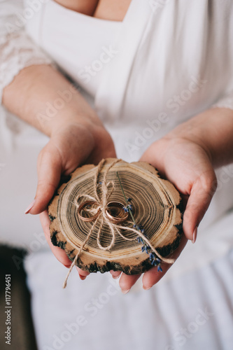 Woman holds wedding rings on wooden holder