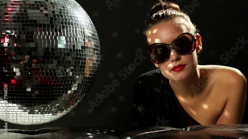 a sexy woman dances with a discoball