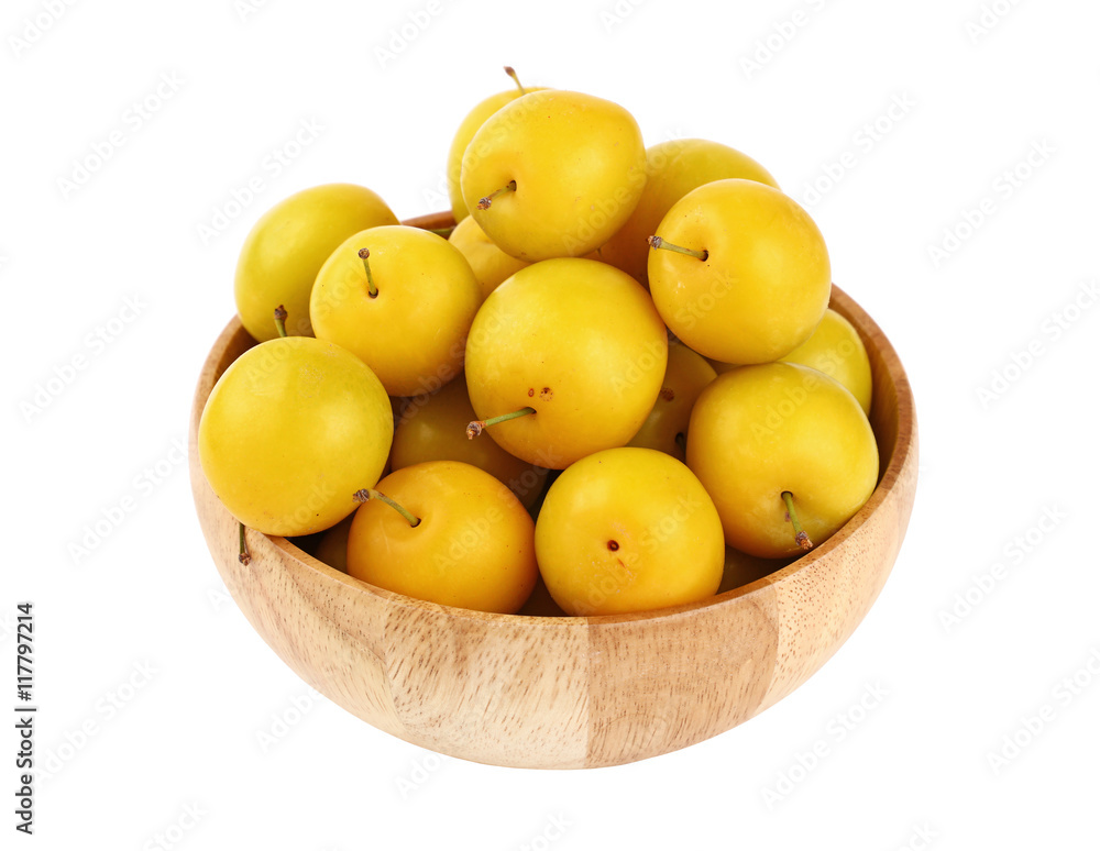 Fresh yellow plums in wooden bowl over white Fresh yellow plums in wooden bowl over white