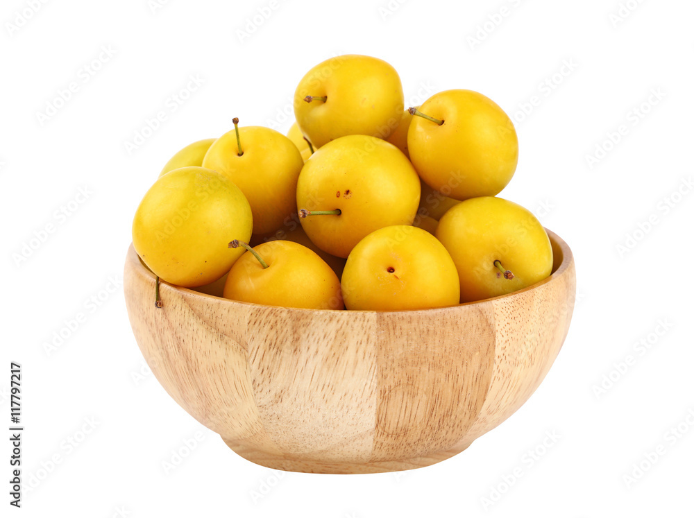 Fresh yellow plums in wooden bowl over white Fresh yellow plums in wooden bowl over white