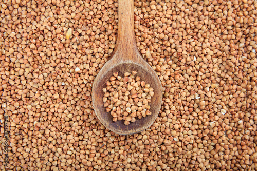 Wooden spoon on buckwheat background