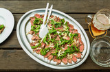 roast beef with arugula and parmesan cheese served on a platter