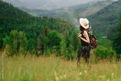 stylish hipster woman with backpack looking at amazing woods an