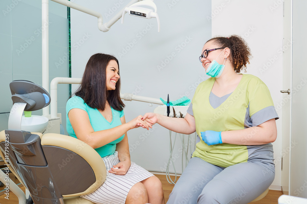 Doctor dentist and patient shake hands at the dental office after the