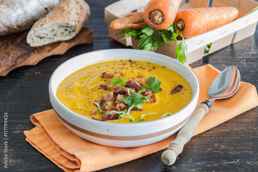 Roasted pumpkin and carrot soup with becon and pumpkin seeds on white wooden background Roasted pumpkin and carrot soup with becon and pumpkin seeds on white wooden background