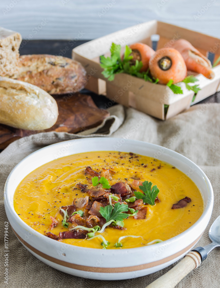 Roasted pumpkin and carrot soup with becon and pumpkin seeds on white wooden background Roasted pumpkin and carrot soup with becon and pumpkin seeds on white wooden background
