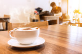 White cup of coffee with smoke on table in cafe.