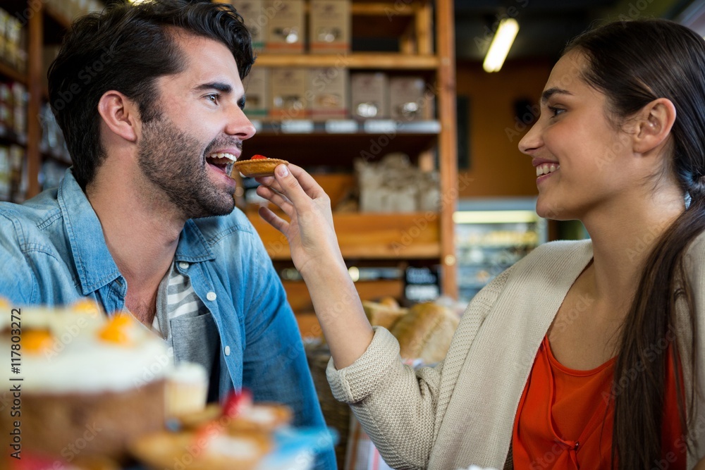 Happy woman feeding man with dessert