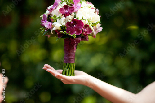 Violet wedding bouquet stands on bride's palm