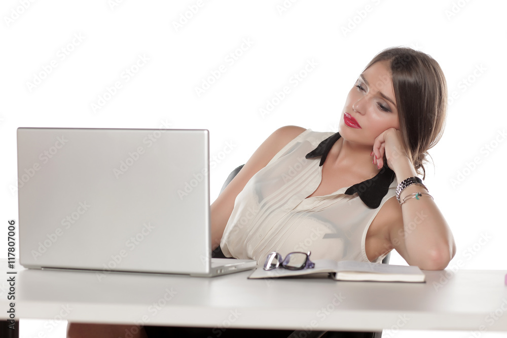 Tired business woman sitting at her desk with a laptop Tired business woman sitting at her desk with a laptop