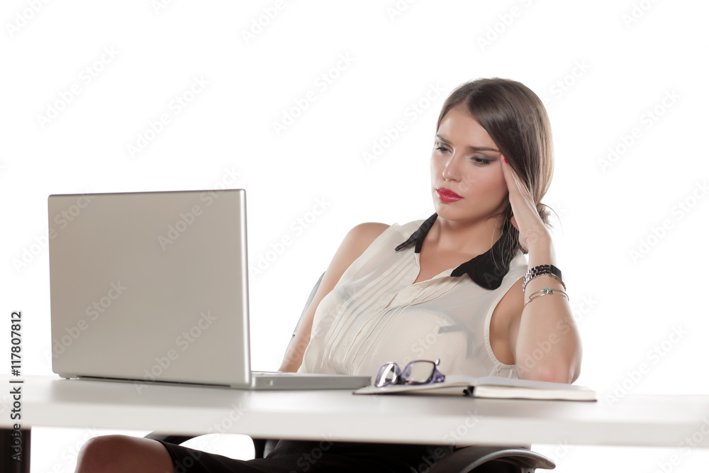 Tired business woman sitting at her desk with a laptop Tired business woman sitting at her desk with a laptop