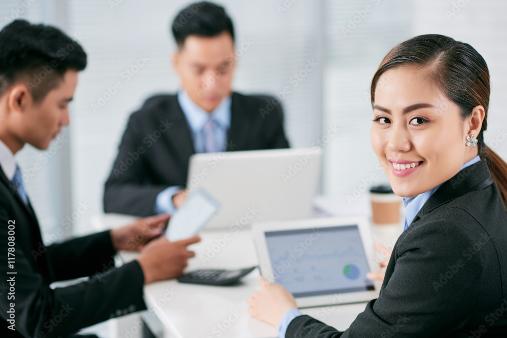 Lovely young business lady looking at camera when sitting at table Lovely young business lady looking at camera when sitting at table