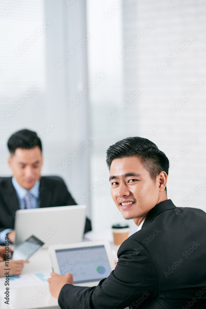 Young Asian businessman with digital tablet smiling at camera Young Asian businessman with digital tablet smiling at camera