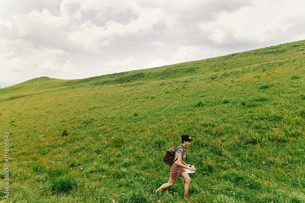 stylish hipster woman traveler walking on hill of summer mountai