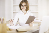 Woman using tablet and doing paperwork
