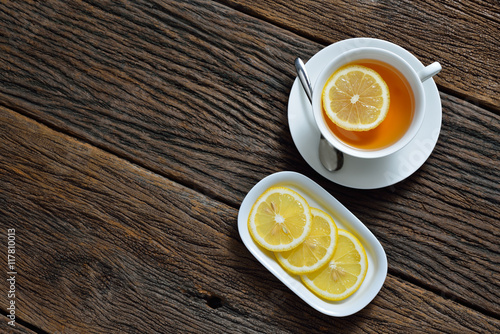 Top view of cup of tea with lemon on wooden table