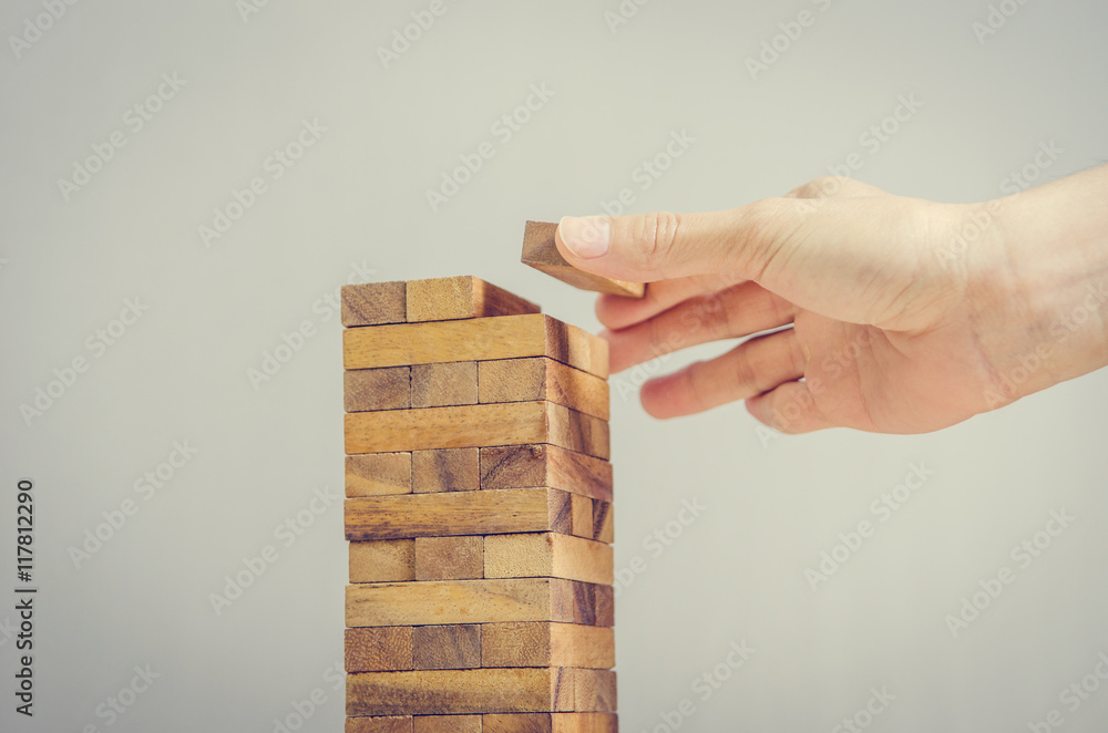 Risk and strategy, planning, hand gambling placing wooden block on a tower. Retro filter effect. Risk and strategy, planning, hand gambling placing wooden block on a tower. Retro filter effect.