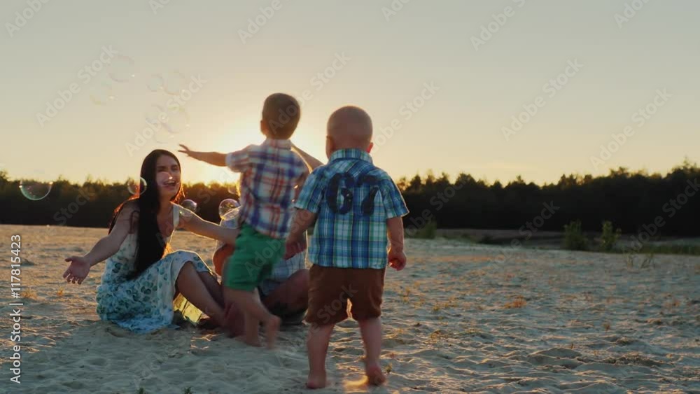 young family having fun with kids - blow bubbles at sunset young family having fun with kids - blow bubbles at sunset