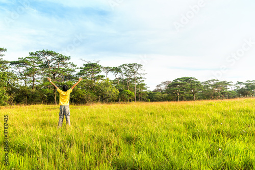 Young man in spreading hand in green meadow.