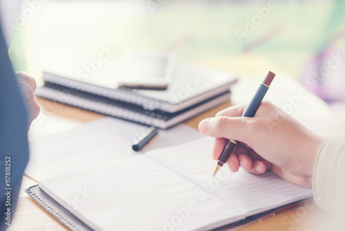  female hands with pen writing on notebook coffee cafe
