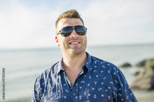 Portrait of mid adult man in blue shirt side beach © Louis-Photo