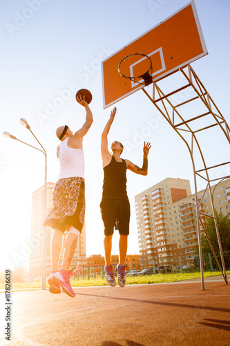 Two guy play basketball at district sports ground. © davstudio