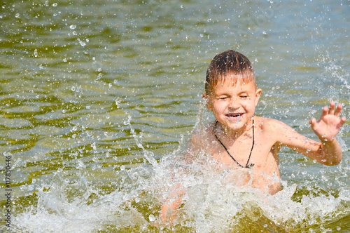 Boy swims in the lake water with a green tint. photo