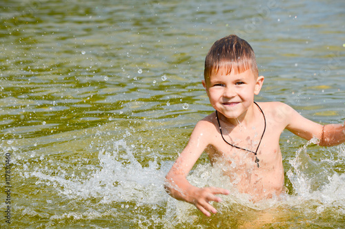 Boy swims in the lake water with a green tint.