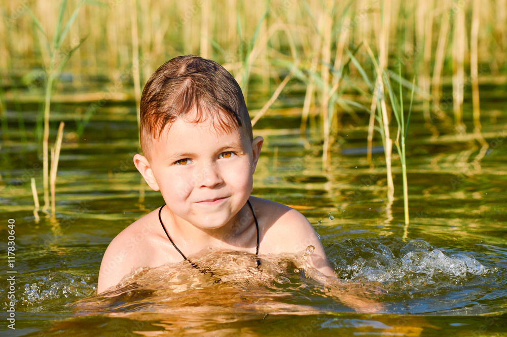 Boy swims in the lake water with a green tint. Boy swims in the lake water with a green tint.