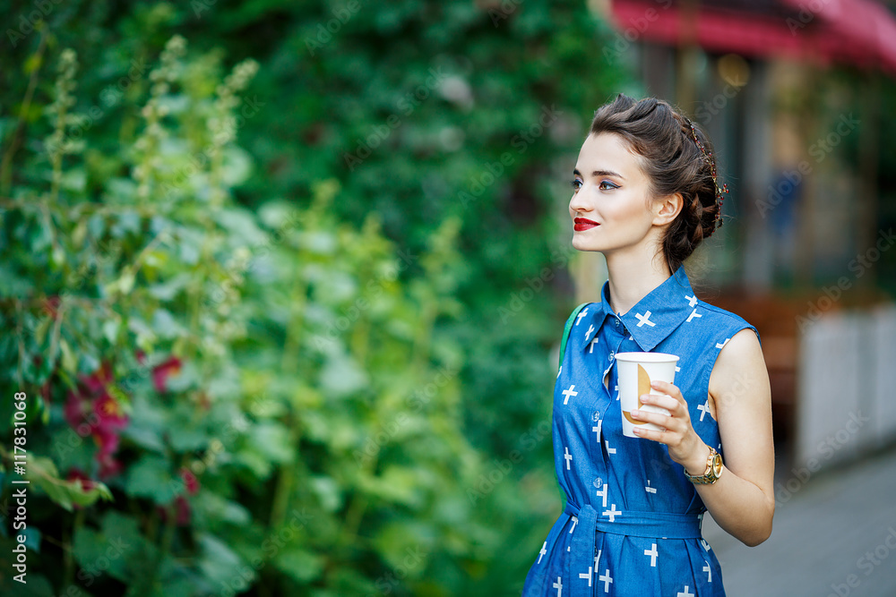 beautiful girl in blue dress holding a coffee in her hand and walks around the city beautiful girl in blue dress holding a coffee in her hand and walks around the city