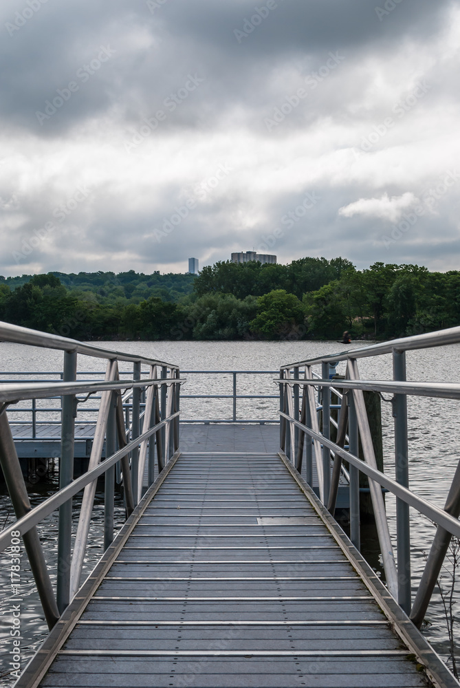 Boat dock. Symmetrical image. Lake view. River view. Blue cloudy sky background. Tree forest background. Forest landscape. Steel frame. Chrome frame dock. Boat launch.