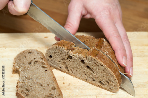 Hands cutting rye bread on a table