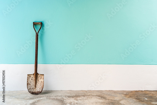old shovel with mint, cyan pastel cement wall background photo