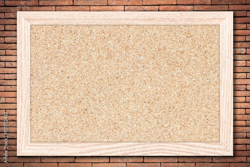 Cork board or Empty bulletin board with a wooden frame on brick wall background with copy space for text or image. photo