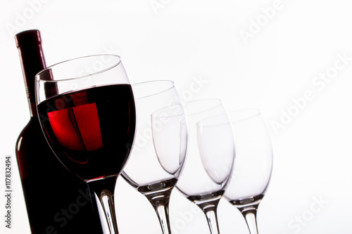 Weinflasche, Weingläser leer und mit Rotwein gefüllt in Reihe und Untersicht, Nahaufnahme