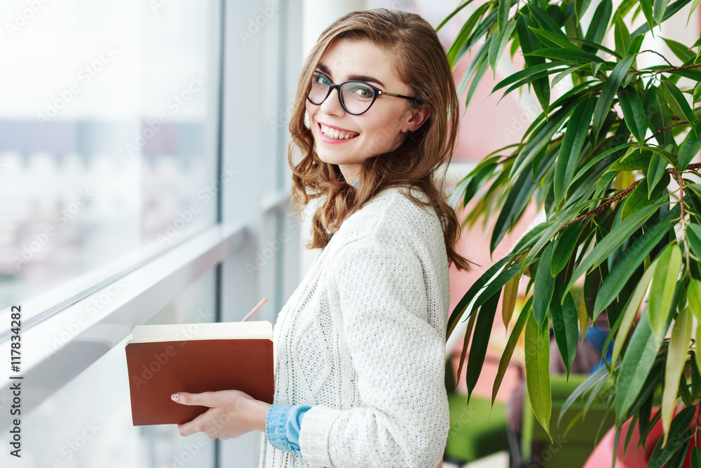Lovely girl with glasses standing with notebook Lovely girl with glasses standing with notebook
