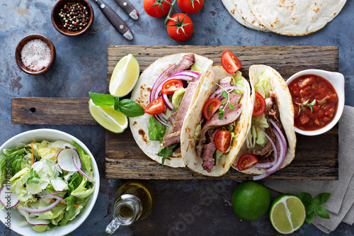 Steak tacos with sliced meet, salad and tomato salsa photo