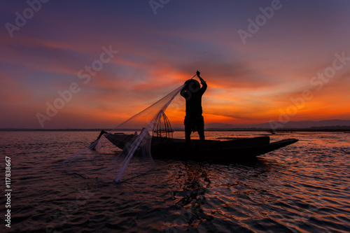 Fotografia, Obraz Silhouette of traditional fishermen throwing net fishing inle lake at sunrise ti