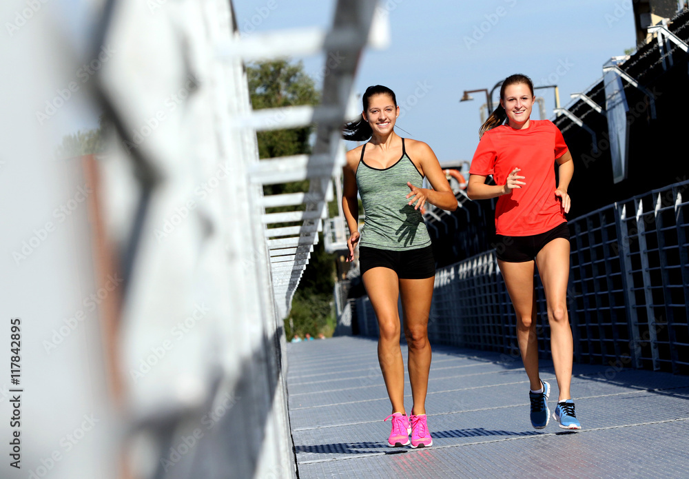 Obraz premium Freundinnen beim Joggen auf einer Brücke/Steg im Sommer