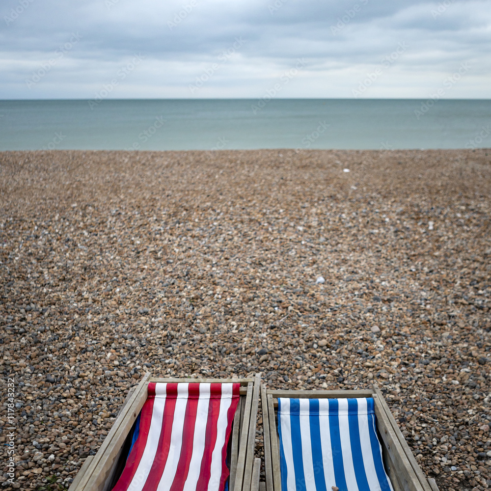postcards from the sea, colorful deck chairs on the pebble beach