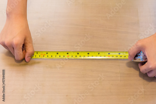 Hand holding measuring tape on wooden table
