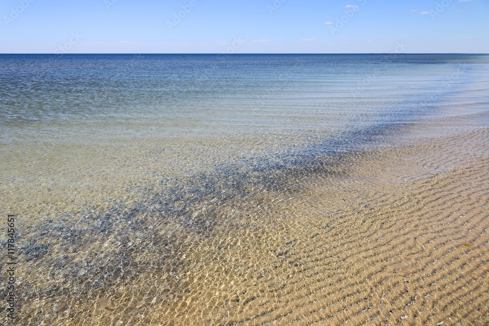 Calm sea surface near coastline. Seascape in sunny day under clear skies.