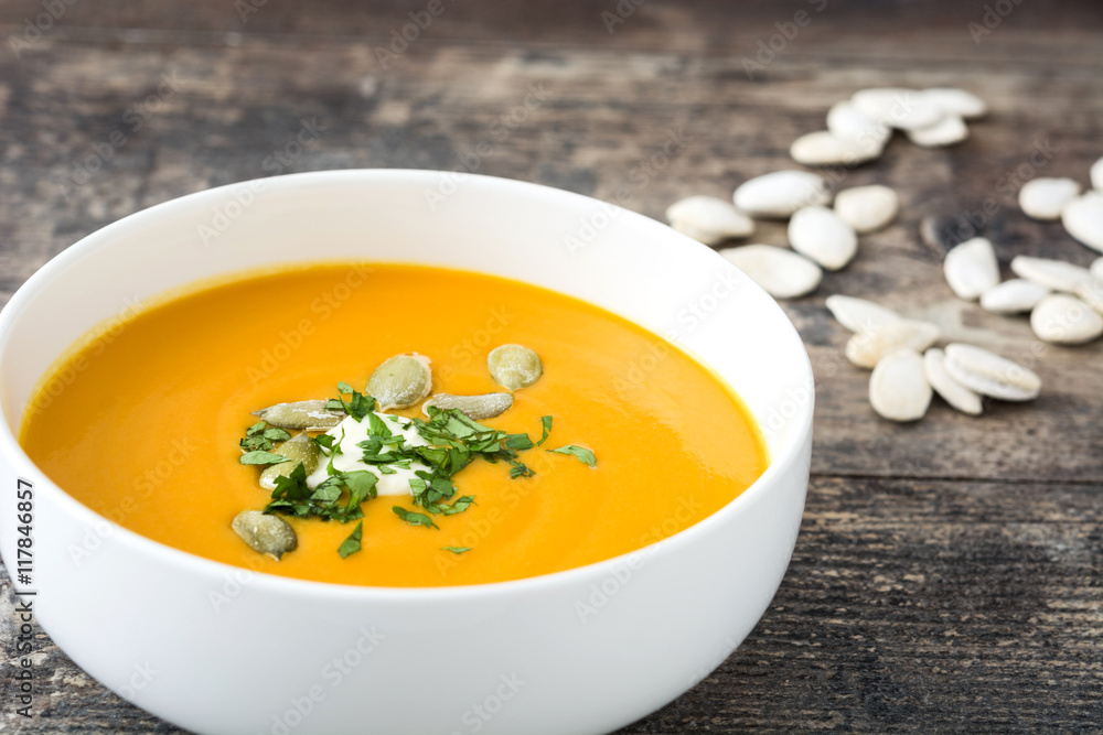 Pumpkin soup with cream and pumpkin seeds on wooden background
Pumpkin soup with cream and pumpkin seeds on wooden background
