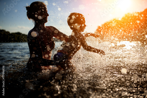 mother swim with baby in blue water at sunset  © goami