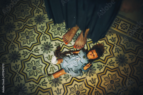 Dool on tiled floor near barefoot female feet