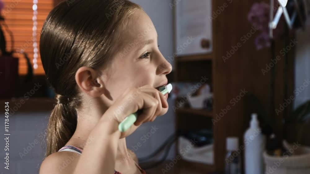 Child girl in pink pyjamas washing and brushing teeth in bathroom Child girl in pink pyjamas washing and brushing teeth in bathroom