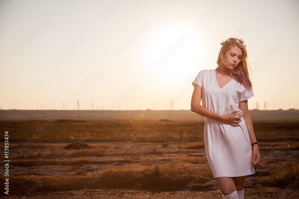 Beautiful woman in white dress posing on the sunset with sexy look. Fashion model in boots and high golf and short dress. Sensitive girl in the fields. Beautiful woman in white dress posing on the sunset with sexy look. Fashion model in boots and high golf and short dress. Sensitive girl in the fields.